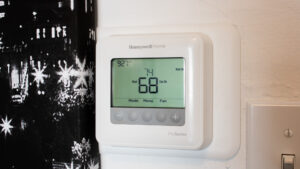 Close-up of a modern smart thermostat being installed on a wall for home energy management.